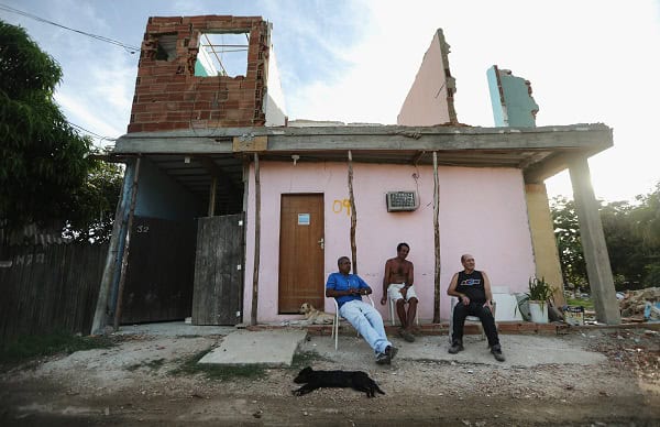 People sit beneath a partially demolished structure in Vila Autodromo. Credit: Mario Tama/Getty