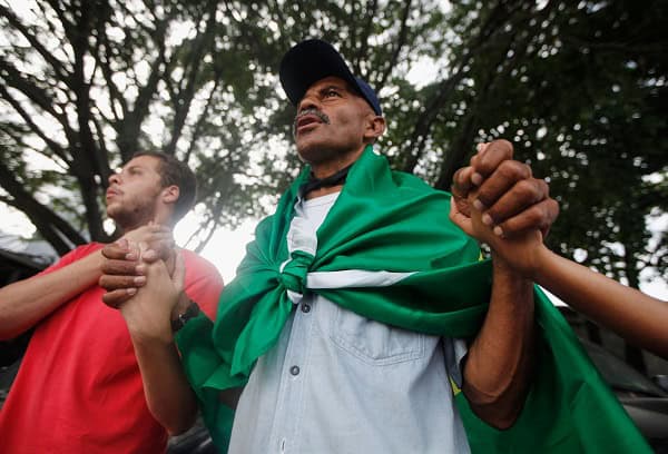 A resident wears a Brazilian flag while protesting demolition work. Credit: Mario Tama/Getty