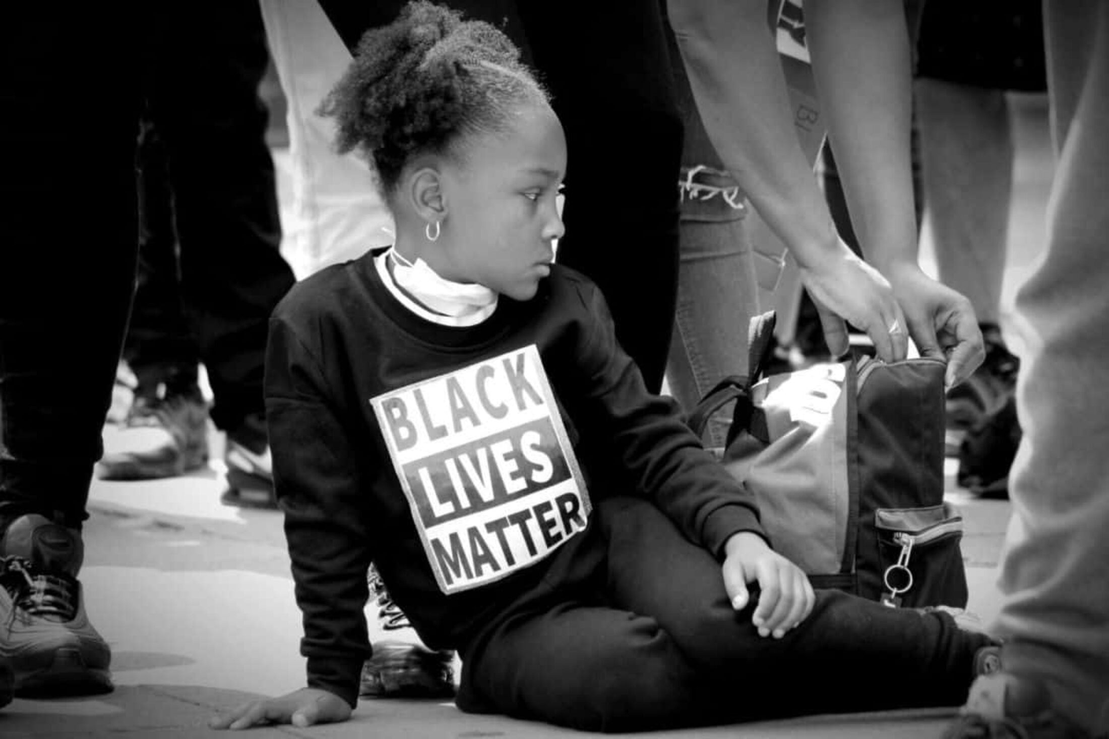 A young protestor asitting at the foot of City Hall in Bristol, listening to the speeches