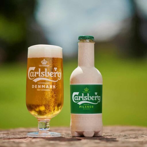 Picture of a Carlsberg beer in a glass and its plant-based bottle.